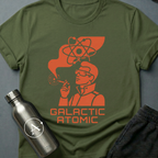 Apsion Outpost graphic t-shirt 'Trusted Since the Empire' in Military Green — atomic-age mascot in dressing gown with sunglasses, smoking under an atom symbol. On-shirt text reads GALACTIC ATOMIC.