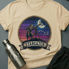 Backyard Astronomer (F) sci-fi t-shirt — a vintage figure at a tripod telescope under a starry sky with a sunset-stripes sun behind — Natural unisex tee — Apsion Outpost