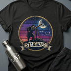 Backyard Astronomer (M) sci-fi t-shirt — a vintage figure at a tripod telescope under a starry sky with a sunset-stripes sun behind — Black unisex tee — Apsion Outpost