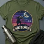 Backyard Astronomer (M) sci-fi t-shirt — a vintage figure at a tripod telescope under a starry sky with a sunset-stripes sun behind — Military Green unisex tee — Apsion Outpost