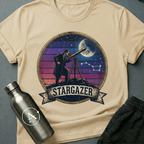 Backyard Astronomer (M) sci-fi t-shirt — a vintage figure at a tripod telescope under a starry sky with a sunset-stripes sun behind — Natural unisex tee — Apsion Outpost
